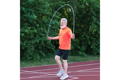 An older man jumps rope on a running track.